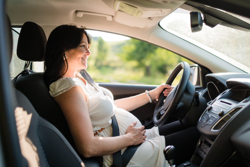 Pregnant woman driving with safety belt on in the car